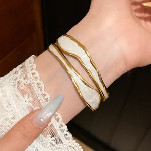 Elegante open armband van roestvrij staal met wit emaille en gouden randen.