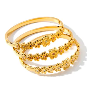 Detailopname van drie 18k vergulde roestvrijstalen armbanden met CZ bloemmotieven
