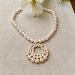 Elegant French style pearl necklace with large circular openwork pendant on linen