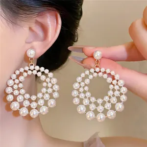 Close-up of French-style hollow circular pearl hoop earrings shown on a model's ear