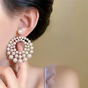 Close-up detail of elegant hollow tiered circular pearl earrings on a model's ear