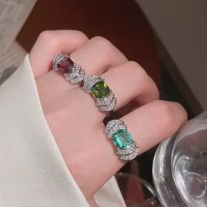 Vista de cerca de tres anillos de circón de colores con forma de abanico en los dedos