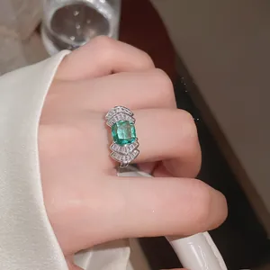 Detalle de un anillo abierto con forma de abanico geométrico y circonita verde brillante.