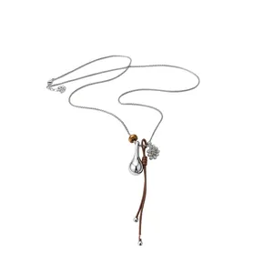 Minimalist silver chain and brown leather cord necklace with a polished teardrop pendant