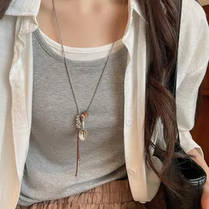 Minimalist long sweater necklace featuring a silver spoon pendant and leather cord accent.