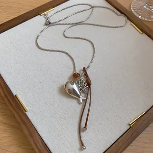Macro view of a minimalist silver fish pendant necklace with brown leather cord details
