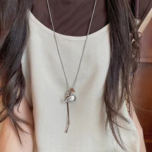 Detailed view of a minimalist silver whale necklace with brown resin bead on a model