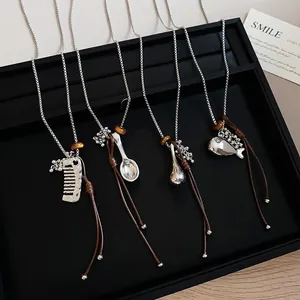 Detail of minimalist necklaces with fish, comb, and spoon pendants on leather cords