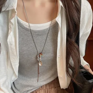Close-up of minimalist Korean style long sweater necklace with spoon and bead charms