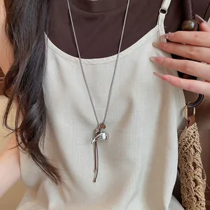 Minimalist silver fish pendant necklace with brown leather cord and resin bead details