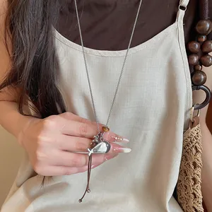 Macro view of a minimalist silver resin fish pendant on a leather cord sweater chain