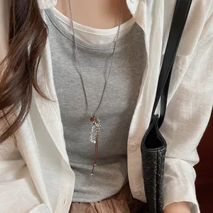 Detail view of a minimalist silver fish pendant necklace with leather cord on a model
