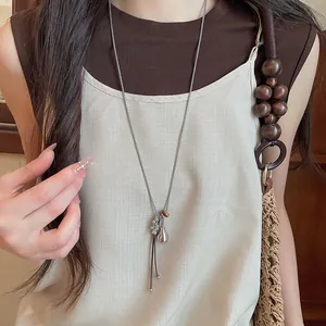 Detail view of a minimalist long necklace with silver teardrop pendant and cord