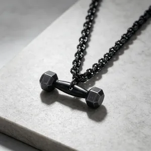 Gros plan d'un pendentif haltère noir vintage sur une chaîne en acier inoxydable pour homme