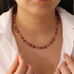 Detail view of a gold-tone stainless steel necklace with red and pink crystal flower charms.