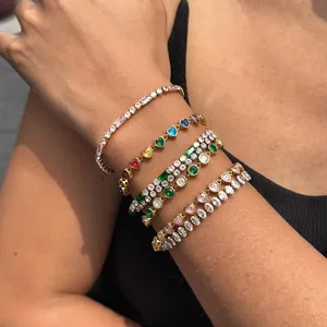 Dettaglio di bracciali placcati oro con zirconi colorati sul braccio.