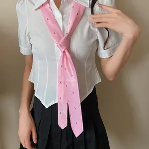 Vista detallada de una dulce corbata de seda rosa estampada con una blusa blanca