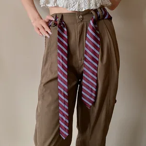 Vista detallada de una corbata de rayas burdeos usada como cinturón de moda elegante