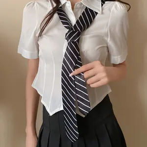 Detalle de una corbata a rayas blancas y negras con una camisa blanca de uniforme JK