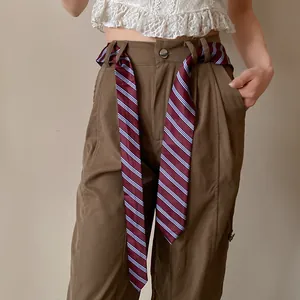 Detalle de corbata de rayas granate usada como un elegante accesorio de cinturón.