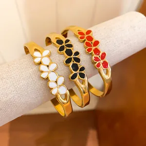 Close-up of vintage gold flower bangles with white, black, and red enamel details