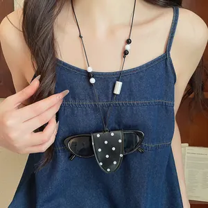 Portable black polka dot leather sunglasses holder necklace worn as a stylish accessory