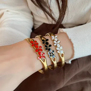 Detail view of vintage enamel flower bangles in red, black, and white on wrist