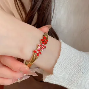 Macro detail shot of a vintage gold-toned bracelet with red enamel flowers on a wrist
