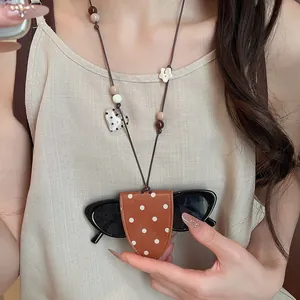 Detailed close-up of a stylish polka dot leather glasses holder worn as a necklace lanyard