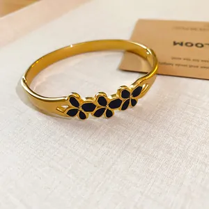 Exquisite vintage gold-tone bangle featuring elegant black enamel flower details on a textured background