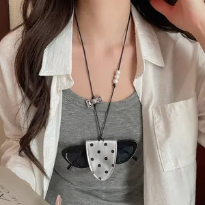 Detailed macro shot of a polka dot leather glasses holder necklace on a female model