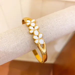 Close-up detail of a vintage style golden bangle featuring three white enamel flowers