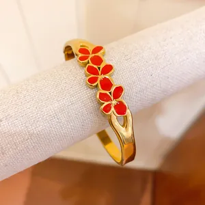 Close-up of vintage gold bangle featuring three vibrant red enamel flower charms