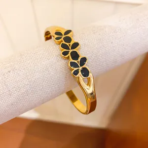 Detail view of vintage gold bangle with black enamel flowers and split band design