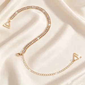 Close-up detail of sparkling double-row rhinestone bra strap on cream satin background