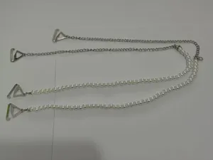 Detail view of pearl and silver metal chain bra straps with triangular hooks for lingerie.