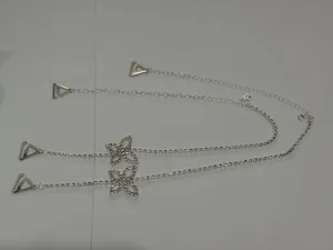 Detailed view of silver rhinestone butterfly decorative bra straps on white background