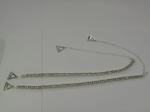 Close-up of silver rhinestone bra straps with adjustable chain and triangle hooks.