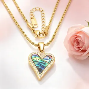 Détail d'un pendentif en forme de cœur avec incrustation d'abalone et bordure en cristal.