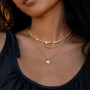 Detailansicht einer stilvollen dreilagigen Goldkette mit eleganten Tropfen-Zirkonia am Modell