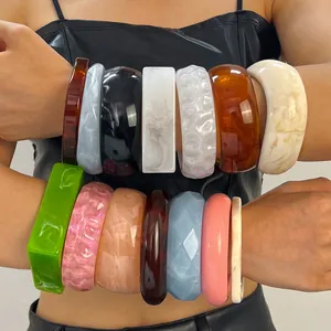 Variety of vintage marbled resin wide bangles in multiple colors and patterns on arms.