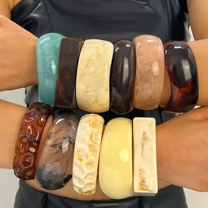 Detailed view of vintage marbled resin wide bangles in various colors worn stacked on arms