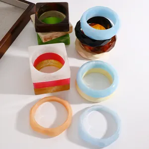 Detail view of retro marbled resin wide bangles in multiple colors and geometric shapes.