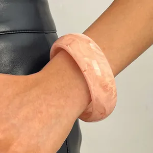 Close-up of retro marbled resin wide bangle bracelet in peach pink