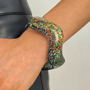 Close-up detail of a vintage wide resin bangle with colorful holographic glitter on arm