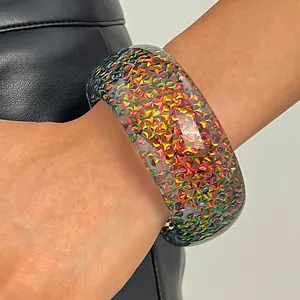 Detailed close-up of a wide resin bangle with colorful shimmering triangular flakes inside