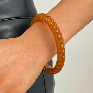 Detail view of a vintage amber resin wide bangle with spiral texture on a wrist