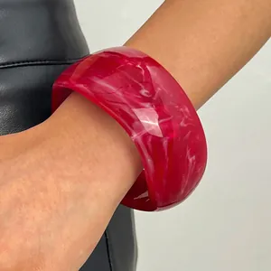 Detailed view of a vintage red marbled resin wide bangle with glossy finish on a wrist