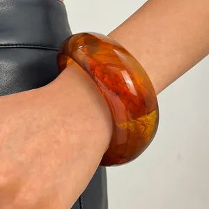 Detailed macro view of vintage marbled amber resin wide bangle bracelet on a female wrist