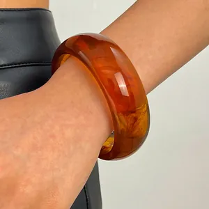 Close-up shot showing the intricate marbled texture of a vintage amber resin wide bangle.